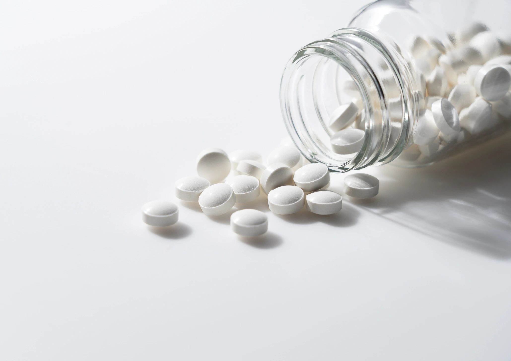 Prescription medication tablets spilling from a bottle